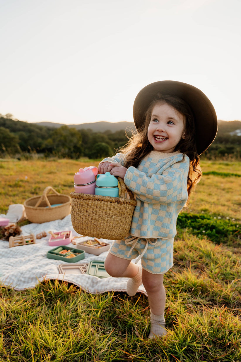 Toddler carrying a basket of water bottles from The Zero Waste People